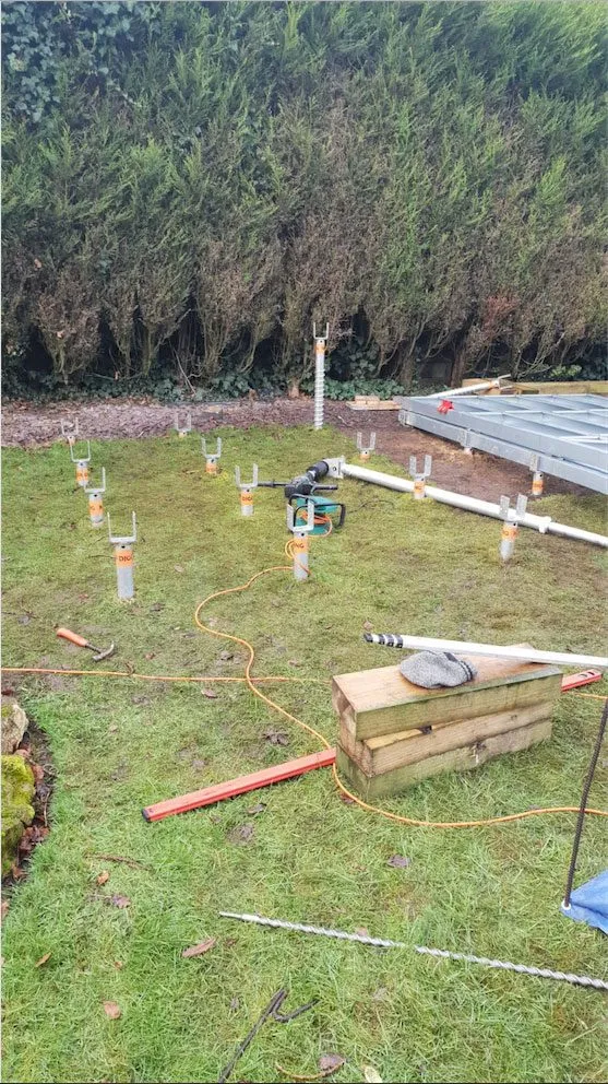Galvanised ground screws set out ready for a no dig foundation installation